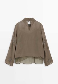 Brun bluse med lange ærmer, en nøglehulsbagside og broderede stjerneskuds-mønstre på ærmerne. Fremstillet af let, semitransparent stof.