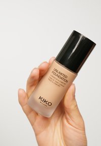 Base Unlimited de KIKO Milano en un frasco de vidrio con tapa negra, presenta un líquido beige, texto en la parte frontal en negro.
