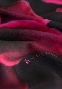 Eșarfă din mătase cu un model floral vibrant roz pe un fundal negru. Include logo-ul "b by Ted Baker" în colț.