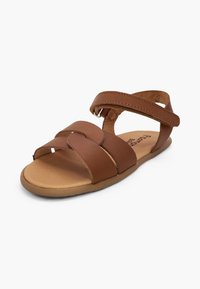 Sandale plate marron avec deux larges brides croisées sur les orteils et une bride à la cheville, présentée sur fond blanc.