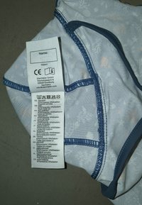 Light blue underwear with a subtle underwater pattern, featuring navy trim and stitching; care label prominently displayed.