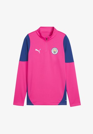 Haut de sport à manches longues rose avec accents bleu marine, col montant, demi-fermeture éclair et logo de Manchester City sur la poitrine. Fabriqué en tissu respirant.