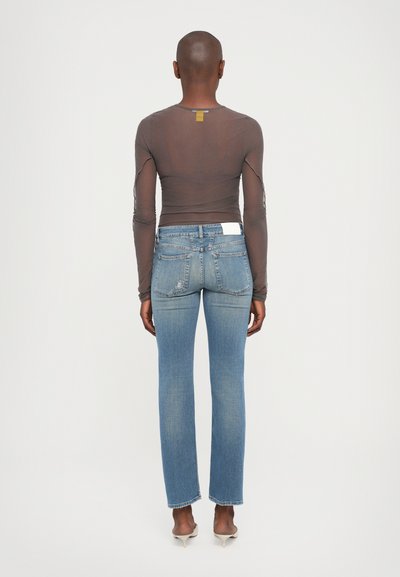 Lange mouwen, transparante bruine top met een slanke pasvorm, gecombineerd met lichtblauwe rechte denim jeans met een wit label op de achterzak.