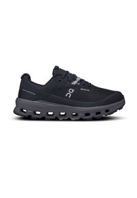 Chaussure de course avec une tige en mesh noir, des accents gris et une semelle épaisse et rembourrée avec des découpes visibles pour une flexibilité et une adhérence accrues.