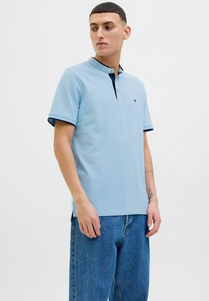 Lichtblauw poloshirt met een kraag, korte mouwen en donkerblauwe accenten. Voorzien van twee knopen bij de kraag en een klein logo op de borst.