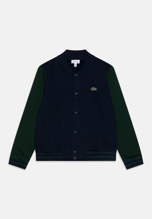 Giacca varsity blu navy con maniche verdi, polsini e vita a costine. Presenta chiusura a bottoni e logo ricamato sul petto.