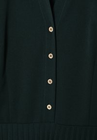 Cardigan verde scuro con finitura testurizzata, dotato di sei bottoni in legno, design a scollo a V e costine verticali lungo l'orlo.