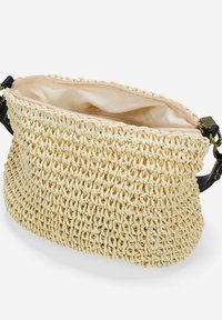 Borsa in paglia intrecciata di un giallo pallido con un esterno texture, chiusura con zip superiore e una fodera interna liscia; presenta una tracolla nera per il trasporto.