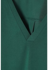 Vihreä v-pääntiepaita, joka on valmistettu pehmeästä ja sileästä kankaasta. Siinä on syvä pääntie ja pieni keskipuolustus takana. Yksinkertainen ja siisti muotoilu.