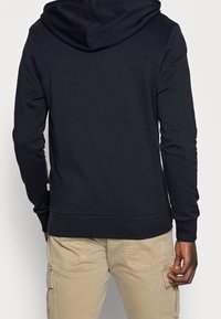 Tmavě modrá mikina s kapucí a dlouhými rukávy s žebrovanými manžetami, se střiženým lemem a minimalistickým designem, vyrobená z měkké látky.