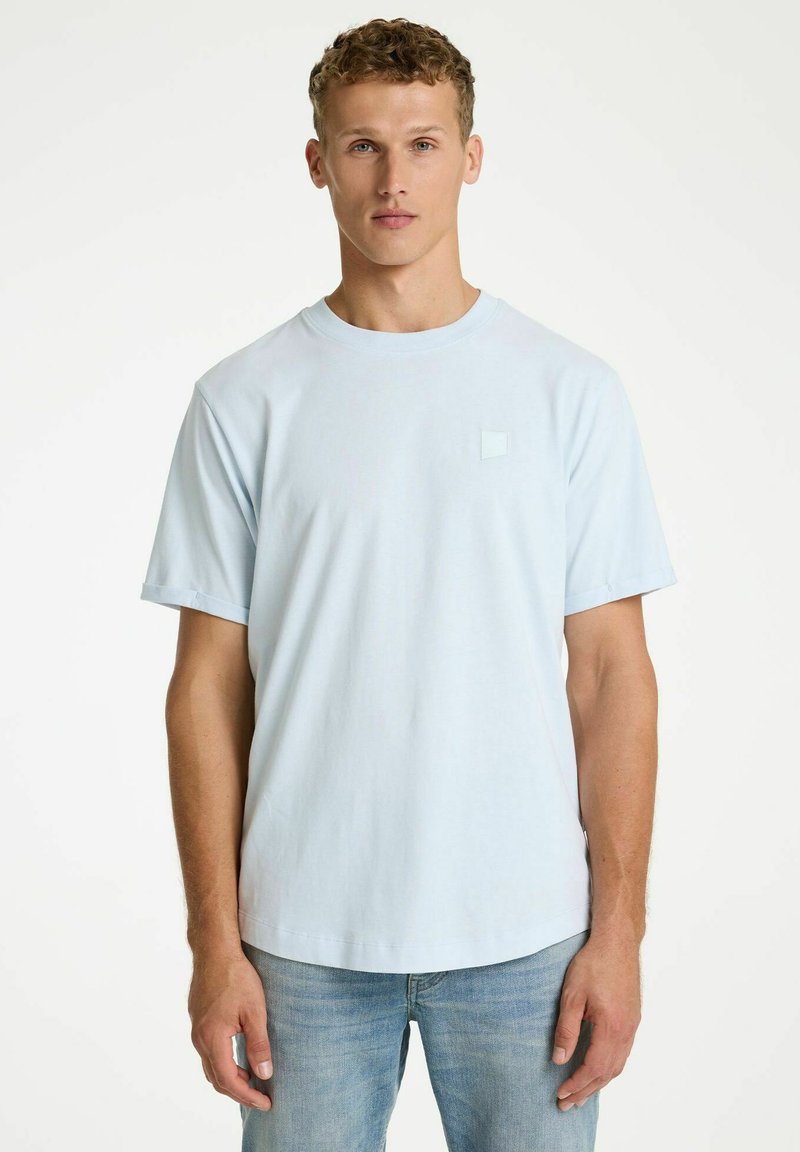 Hele sinine lühikeste varrukatega t-särk, mis on valmistatud pehmest puuvillast. Rinna peal on väike ruudukujuline logo. Ümar kaelus ja lõdvestunud lõige.