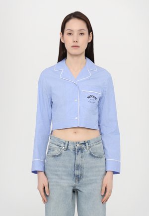 Zkrácená modro-bílá pruhovaná košile s dlouhými rukávy, zapínáním na knoflíky a kapsou se znakem "Moschino". Materiál z bavlny s lemováním.