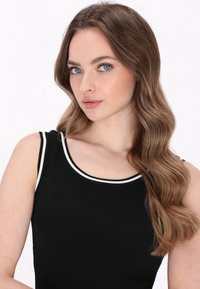 Schwarzes, geripptes Tanktop mit weißem Akzent am Ausschnitt; verfügt über breite Schulterträger und eine figurbetonte Silhouette. Glatte Textur.
