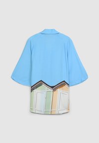 Robe in stile kimono di colore blu chiaro con un design stampato di cottage sulla spiaggia in verde e arancione sul bordo, con una texture liscia e maniche aperte.