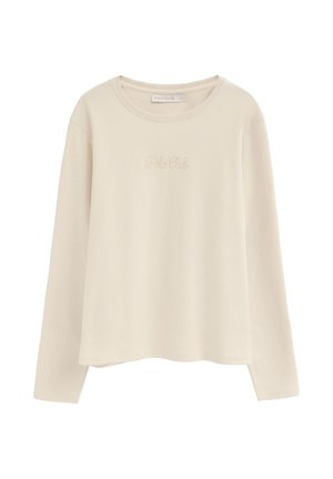 Chemise beige à manches longues et col rond avec une broderie discrète "Polo Club" sur la poitrine et une petite étiquette de marque à l'intérieur de l'encolure.
