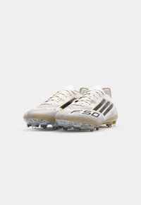 White soccer cleats with black accents, featuring a textured design, prominent lacing system, and a lightweight, aerodynamic shape.