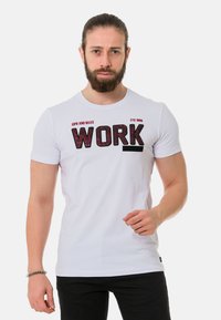 Weißes Baumwoll-T-Shirt mit fettem schwarzen Text "WORK" und roten Akzenten, kurzen Ärmeln und einem Rundhalsausschnitt. Einfacher und lässiger Stil.