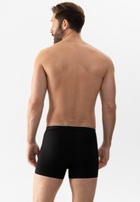 Boxer shorts noirs avec une texture douce et un ajustement serré. Présente une ceinture grise contrastante avec le nom de la marque subtilement embossé.