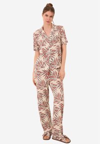 Korte mouwen pyjama set van lichte stof met een bladerenprint in tinten rood en teal, met een button-up shirt en losse broek.
