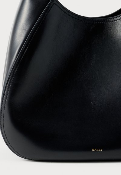 Mustast nahast käekott kõverate vormidega, nähtavate õmblustega ja väikese kuldse "BALLY" logoga alumises paremas nurgas.
