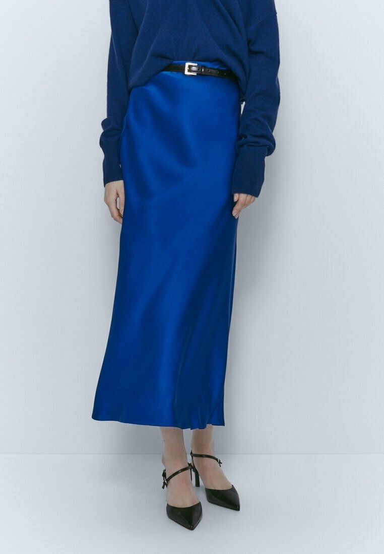 Blaue Satin-Midirock mit glatter Textur, tailliertem Bund und schwarzem Gürtel. Kombiniert mit schwarzen spitzen High Heels.