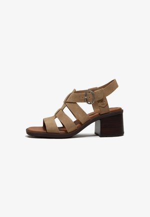 Sandalo aperto in camoscio marrone con tacco a blocco, più cinturini e fibbia regolabile sulla caviglia.