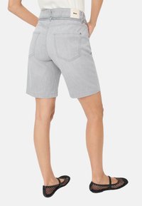 Grijze denim broekshorts met een middelhoge tailleband, twee achterzakken en een gestikte zoom, gecombineerd met zwarte mesh ballerina's.