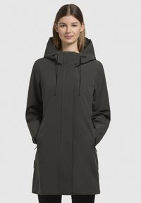 Cappotto impermeabile verde scuro con colletto alto, cappuccio regolabile, tasche con zip e un design elegante e minimalista.