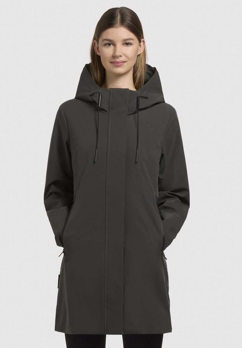 Cappotto impermeabile verde scuro con colletto alto, cappuccio regolabile, tasche con zip e un design elegante e minimalista.