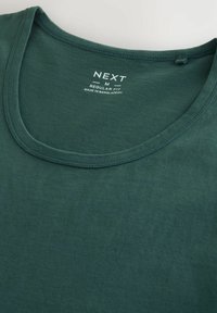 Mørkegrøn bomulds t-shirt med rund halsudskæring. Etiketten viser "NEXT", størrelse "M", og "REGULAR FIT", med en blød tekstur.
