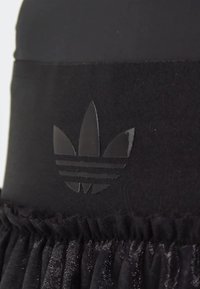 Black sportswear featuring a textured waistband with a matte black Adidas trefoil logo and soft, pleated fabric at the bottom edge.