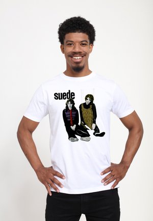 Hvid bomulds t-shirt med grafik af to siddende figurer i sort og gul, med ordet "suede" trykt med fed sort tekst.
