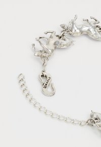 Ezüst lánc karkötő, finoman kidolgozott unikornis charmokkal és "MAPLE" felirattal ellátott horogzárral, kiemelve játékos témáját.