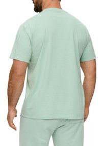 Miętowa koszulka z krótkim rękawem, z okrągłym dekoltem, wykonana z miękkiej bawełny, z prostym dołem i luźnym krojem.