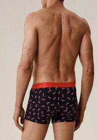 Bokserki w kolorze granatowym z powtarzającym się wzorem czerwono-białych skarpet. Czerwony elastyczny pas i dopasowany krój.