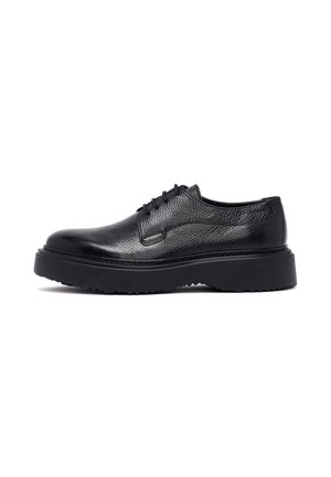 Zapatos de cuero negro con cordones, acabado texturizado y suela de goma gruesa, con costuras prominentes y diseño de punta redonda.