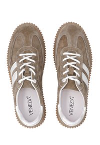 Een paar tan suède sneakers met witte strepen, witte veters en gekartelde rubberen zolen, van bovenaf bekeken.