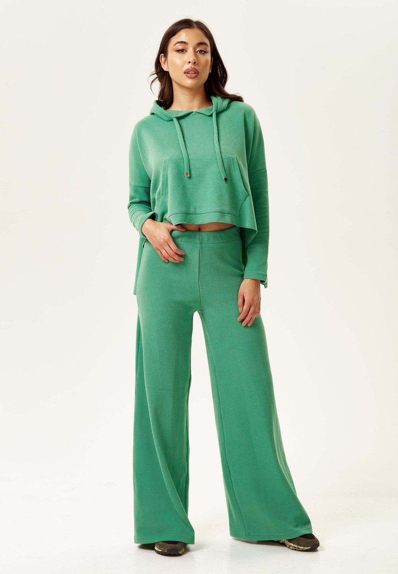 Green lounge set featuring a cropped hoodie with drawstrings and a front pocket, paired with wide-leg pants made of a soft, textured fabric.