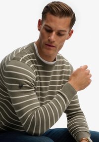 Suéter a rayas en verde oliva y blanco. Diseño de cuello redondo con puños y dobladillo acanalados. Pequeño detalle de logo en la manga izquierda.