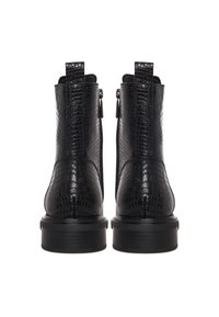 Paire de bottines noires à texture crocodile, avec zips latéraux, languettes de tirage et semelles épaisses en caoutchouc, vues de dos.