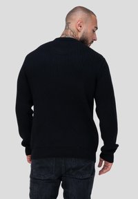 Zwarte geribbelde gebreide trui met lange mouwen en ronde halslijn, met een textuurafwerking en een relaxte pasvorm.