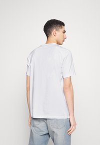 T-shirt bianco a maniche corte realizzato in cotone, con scollatura rotonda, vestibilità comoda e texture liscia senza motivi visibili.