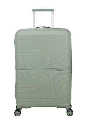 Valigia rigida verde con design diagonale a righe, quattro ruote, manico retrattile e logo American Tourister sulla parte anteriore.