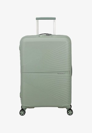 Valigia rigida verde con design diagonale a righe, quattro ruote, manico retrattile e logo American Tourister sulla parte anteriore.