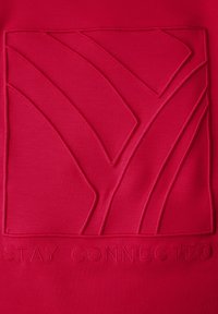 Tessuto rosso con un design astratto in rilievo e il testo "RIMANI CONNESSO" ricamato in basso. Texture liscia, forma moderna.