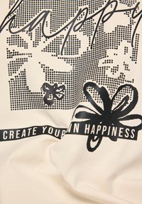 Cremfarbener Stoff mit schwarzem grafischem Text "happy" und Blumen, sowie einem Banner mit der Aufschrift "ERSCHAFFE DEIN EIGENES GLÜCK" am unteren Rand.