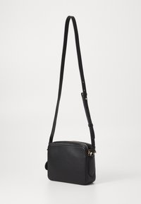 Borsa a tracolla in pelle nera con forma rettangolare, chiusura con zip, tracolla regolabile e dettagli in metallo color oro. Texture liscia.