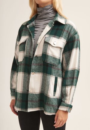 Green and white plaid shirt jacket in soft fabric with two front pockets and silver snap buttons; features a relaxed fit and rolled cuffs.