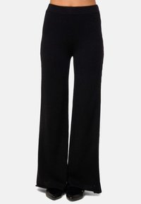 Pantalons larges noirs en tissu doux et extensible, dotés d'une ceinture élastique et de fentes latérales discrètes au bas pour plus de liberté de mouvement.