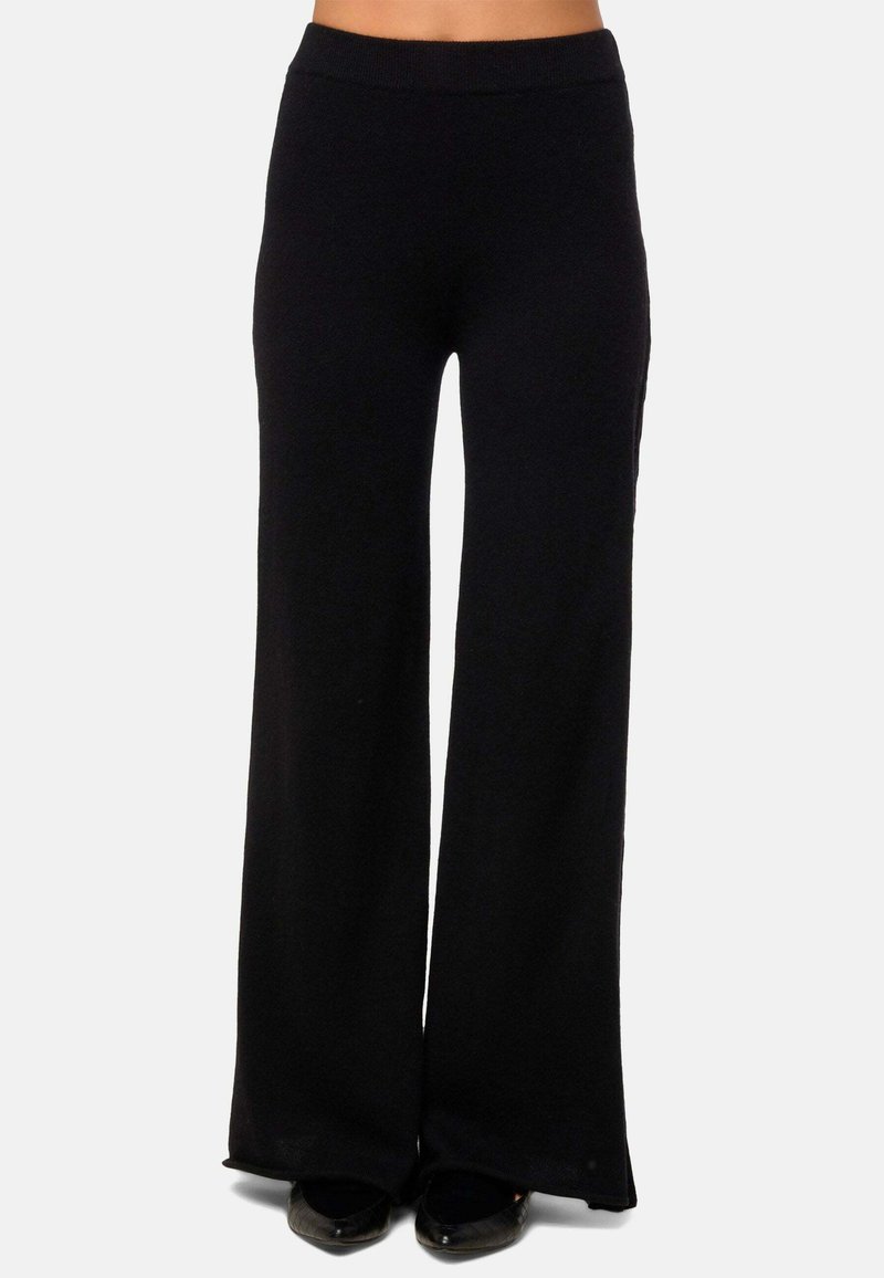 Pantalons larges noirs en tissu doux et extensible, dotés d'une ceinture élastique et de fentes latérales discrètes au bas pour plus de liberté de mouvement.